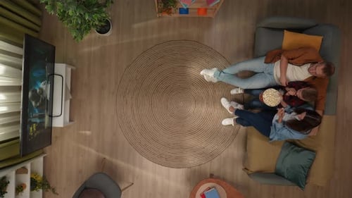 Top View of Living Room Mother Father and Son Sitting on the Sofa Watching Scary Movie on Tv Eating