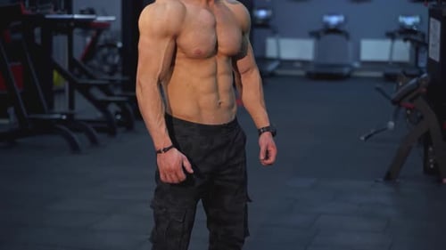 Muscular Man Posing in Gym Flexing Bicep