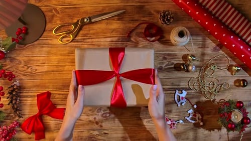 Hands tying Red Ribbon on Christmas Gift