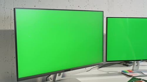 Woman Typing at Desk with Dual Green Screen Monitors