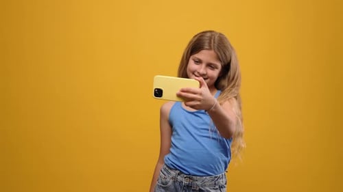Smiling Girl Taking Selfie with Yellow Cell Phone