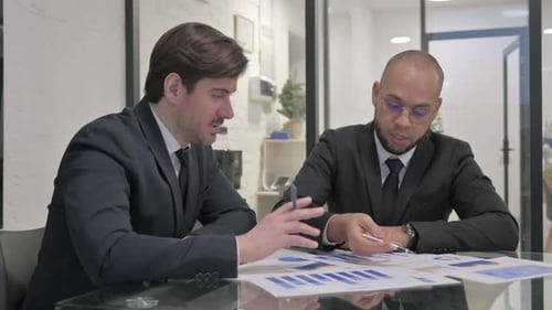Young Businessmen Discussing Paperwork in Office