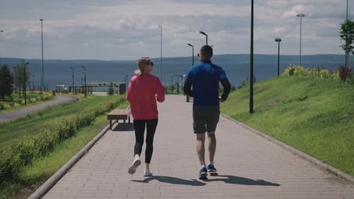Couple sportif faisant une course quotidienne dans le parc de la ville, belle journée d'été et parc paysager, pratique