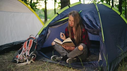 Woman Reading Book in a Tent While Camping