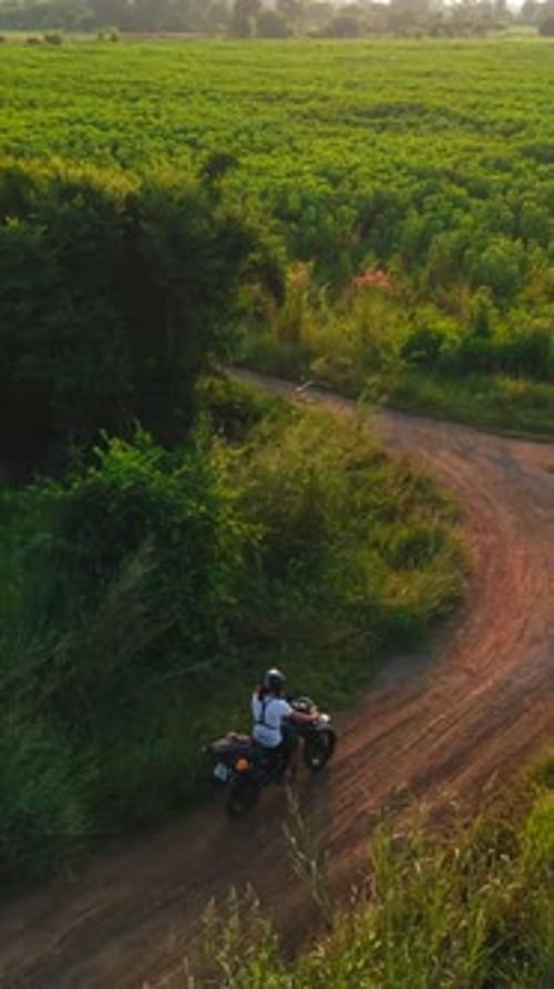 Vue aérienne d'un motocycliste voyageant sur une route rurale traversant des champs cultivés