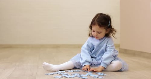 Toddler Child Girl Collects Puzzles on Floor
