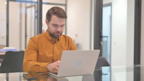 Young Man Working on Laptop in Office