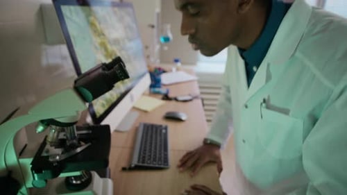 Male Researcher Taking Test Tube while Examining Specimen under Microscope
