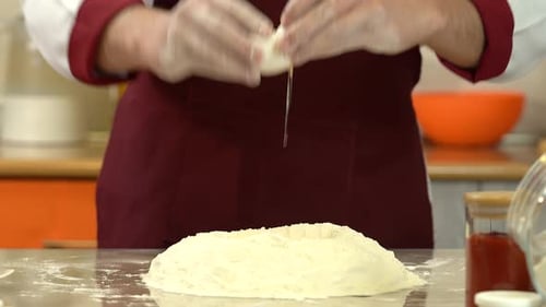 Close view man breaking eggs in the flour. Chef cracking eggs over mound of flour.