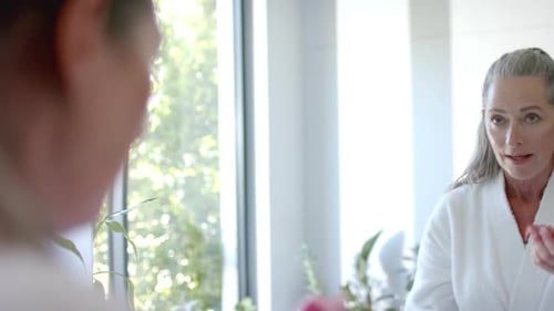 Mature Woman Applies Eye Patches in Bright Bathroom