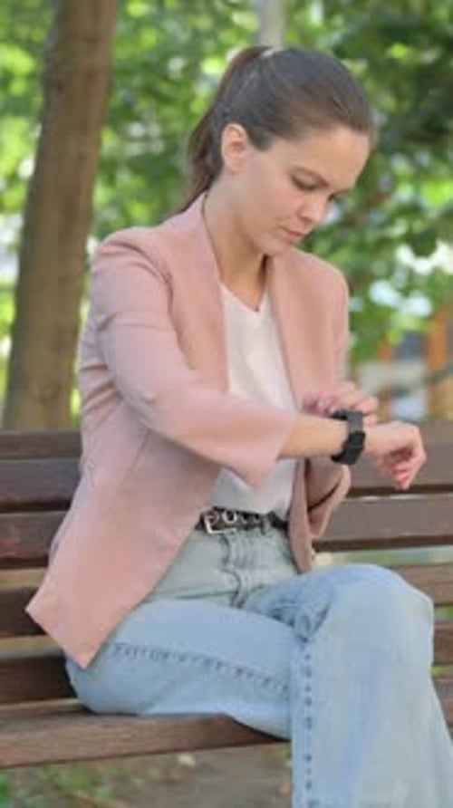 Young Woman Using Smart Watch while Sitting in Park