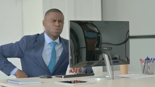Man in Suit Has Back Pain at Desk