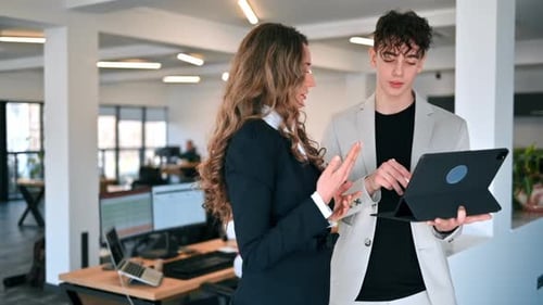 Business session in an office. Woman and a young man discussing business affairs, tablet. Slow motio