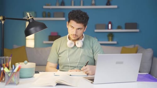 Young Adult Studying at Desk with Laptop and Book