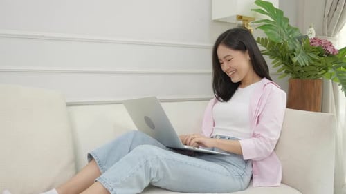 Smiling Woman Using Laptop on Couch at Home