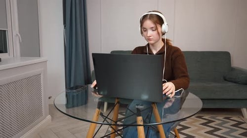 Girl Uses Laptop with Headphones in Home Setting