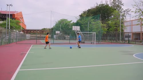Zwei asiatische Sportler beim Fußballspielen im Freiluftstadion.