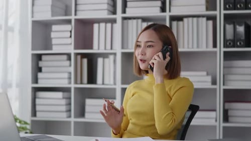 Businesswoman is talking to clients and colleague on the phone and working on laptop in office
