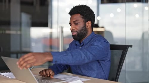 Businessman Finishes Work on Laptop Closes It Leans Back Satisfied in Office