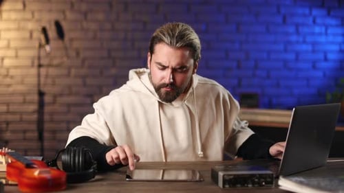 Man Using Laptop and Tablet for Work at Recording Studio