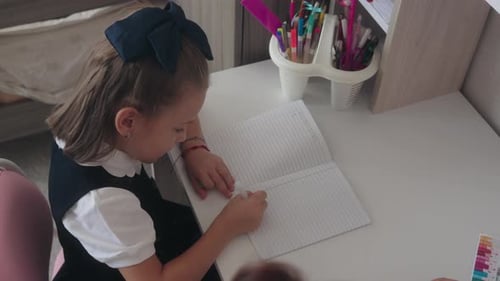 School Girl Writing in Notebook at Desk Homework Education
