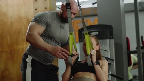A Girl Under the Guidance of Man Fitness Trainer Does Exercises in the Gym The Trainer Supports Her