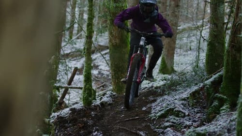 A mountain biker rides a snowy trail in slow motion