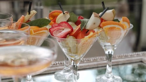 Kompottgerichte mit geschnittenen Früchten neben Gläsern mit Sekt am Buffet