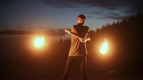 Man Juggling Fire Torches at Night Outdoors