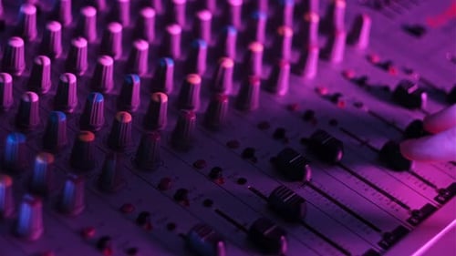 Hand Settings Volume Level Controls on Mixing Console Faders Neon Light CloseUp