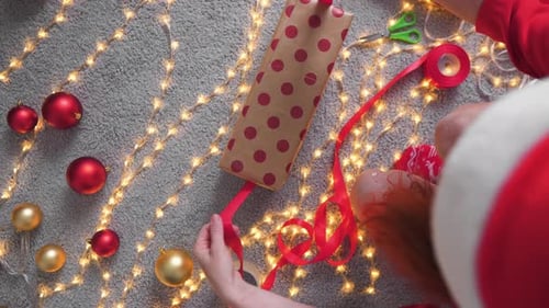 Wrapping Christmas Present with Red Ribbon Overhead