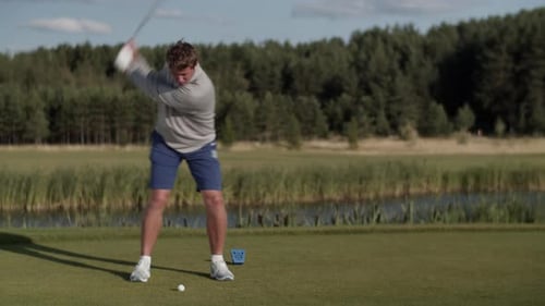 Young Golfer Strikes Golf Ball Playing on Lush Green Course