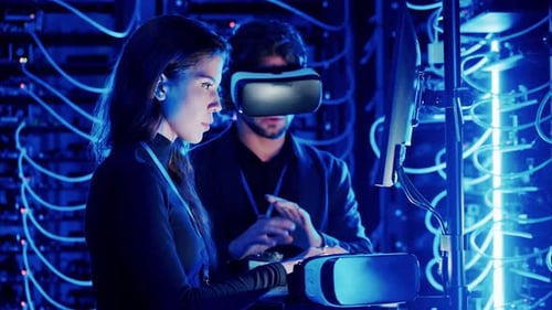 Woman programming in a server room while a man is using a Virtual Reality headset