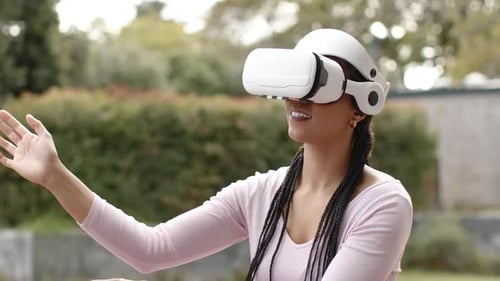 Mulher estendendo os braços enquanto o fone de ouvido é ativado, interagindo com objetos de realidade virtual mostrando surpresa no pátio