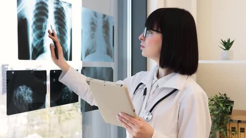 Female Doctor Examining Xray Images with Tablet in Office