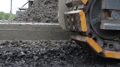Close-up of caterpillar tread of crawler slowly moving along edge of concrete roadbed