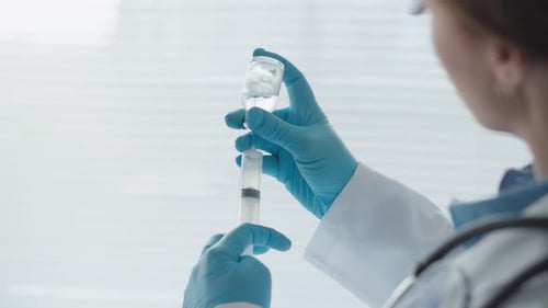 Medical Professional Draws Liquid from Vial with Syringe