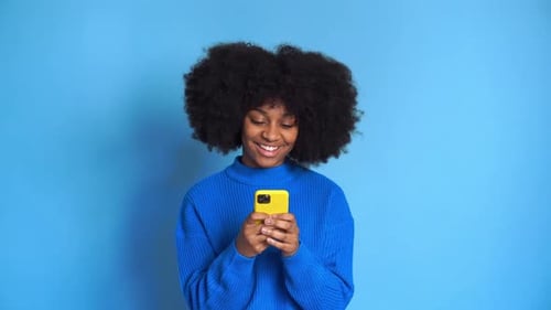 Woman Smiling at Yellow Smartphone on Blue Background