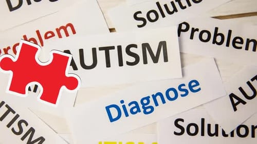 Animation of red and yellow puzzle pieces falling over autism text on white background