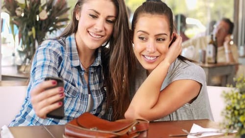Two Smiling Women Taking Selfie at Cafe Together