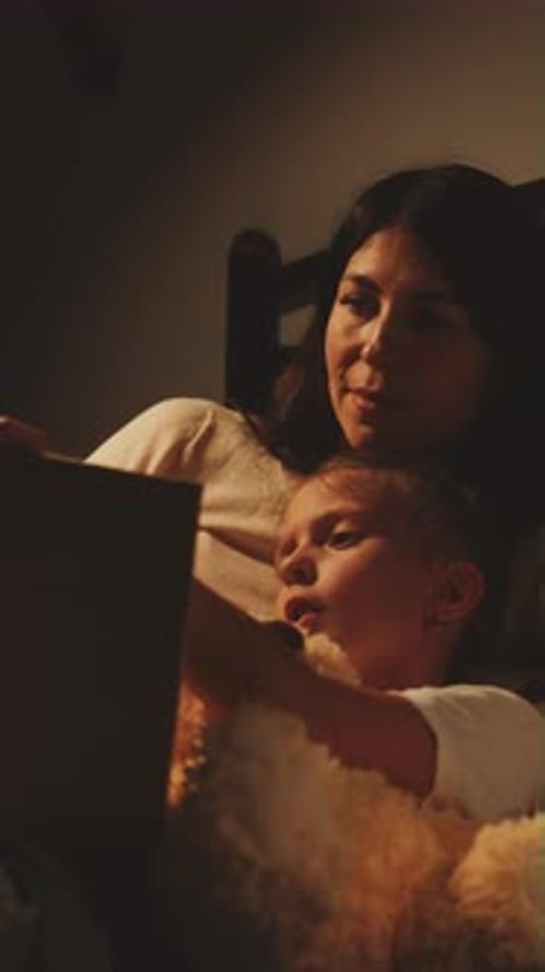 Woman and Child Reading Tablet in Bed With Dog