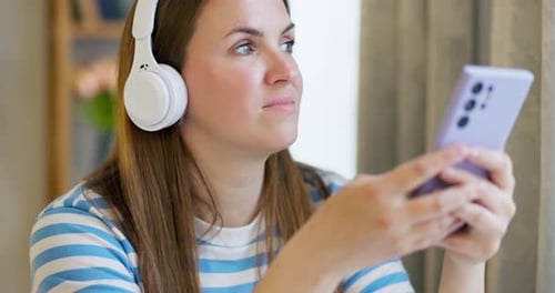 Woman in Wireless Headphones Listening to Music in the Lounge at Home