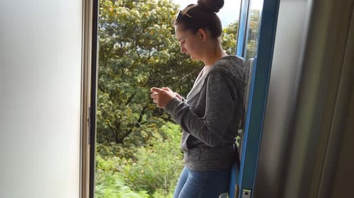 Young Woman Using Smartphone on a Scenic Train Ride