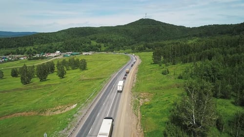 Aerial View of an Intercity Highway with Traffic Going Through Green Meadows and Trees on a Sunny