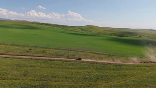 Black Suv Driving on a Dusty Road Through Green Fields