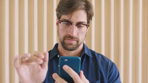 Man with glasses and phone to scroll on social media, mobile media app or on website while happy
