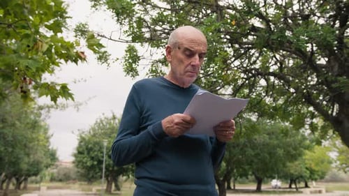 Surprised Man Reading Document in Park Setting