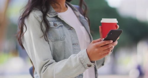 Smiling Woman Using Smartphone While Holding Coffee