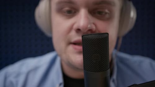 Extreme Close Up View of Young Radio Host in Headphones Who Sits in Recording Studio in Blue Shirt