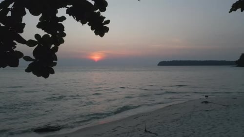Peaceful Tropical Sunset Over Gentle Ocean Waves and Sandy Beach